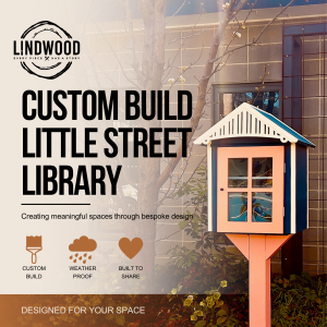 Custom-built little street library with coral door and navy blue roof, displayed in garden setting — Lindwood handcrafted design