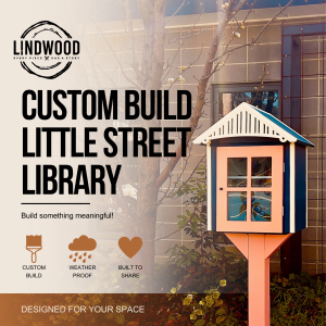 Custom-built little street library with coral door and navy blue roof, displayed in garden setting — Lindwood handcrafted design